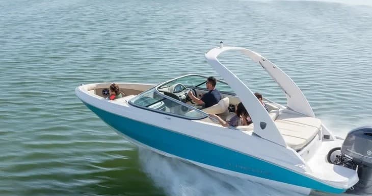 Turquoise speedboat cutting through calm bay waters with driver