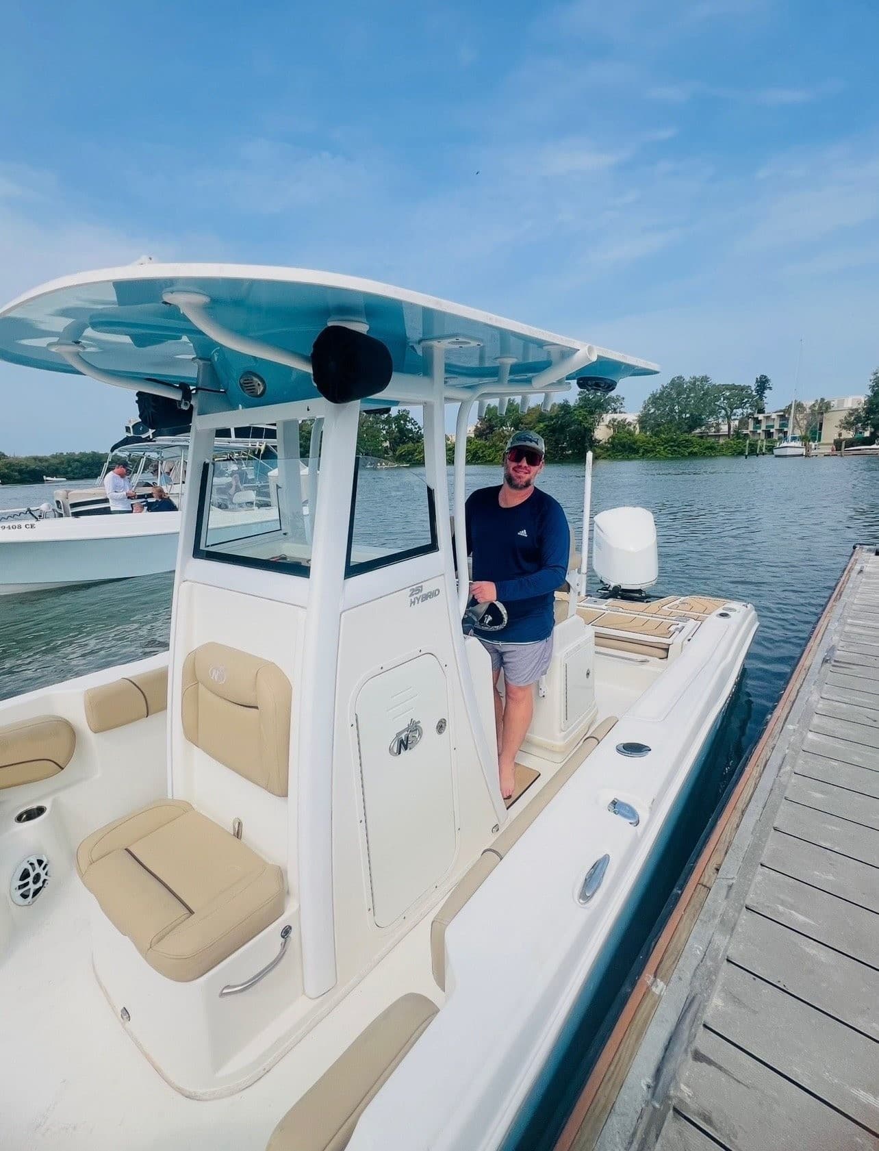 Angler standing on center-console boat moored at sunny marina dock
