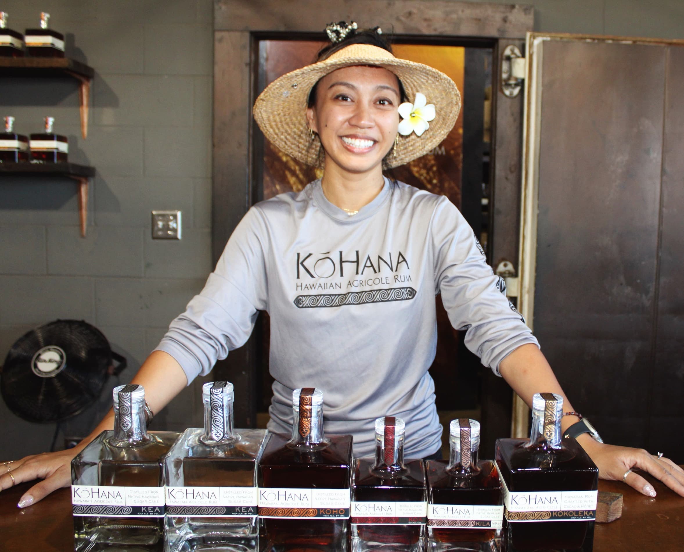 Distillery tasting host smiling behind rum bottles at indoor bar