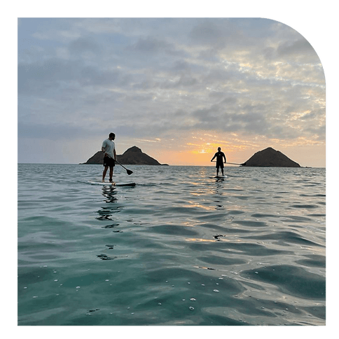 Stand-up paddleboarders at sunrise near twin islets, Oahu