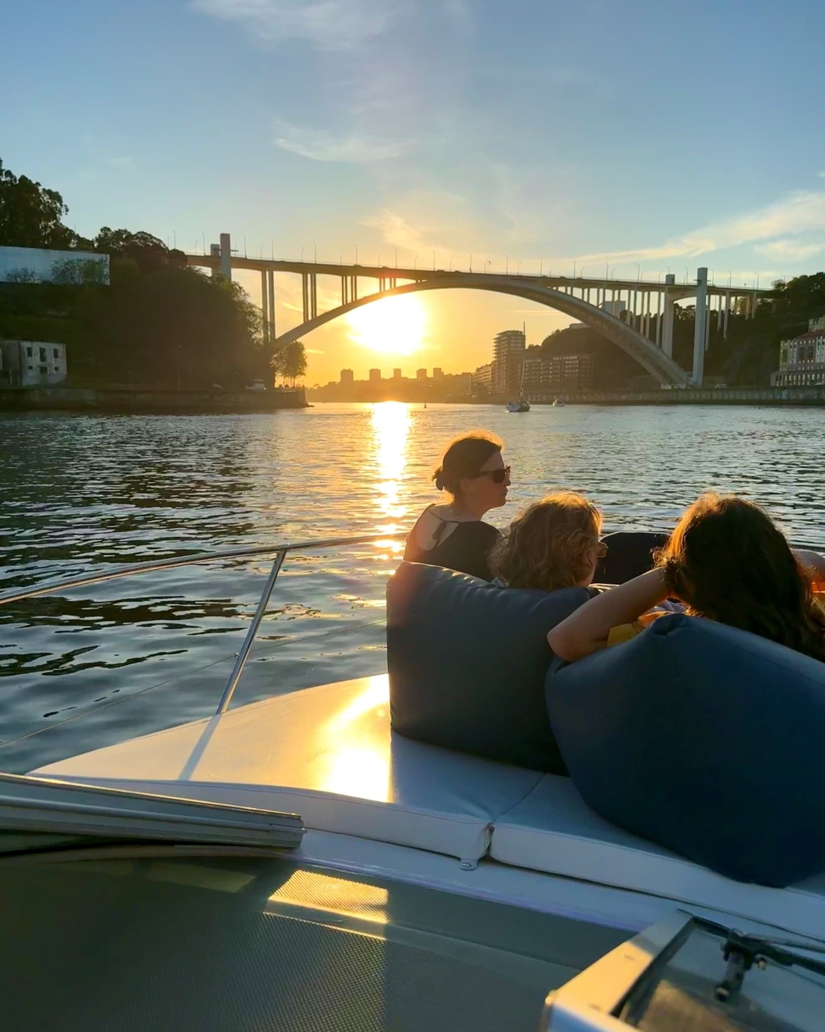 Group boating at sunset on river with arched city bridge