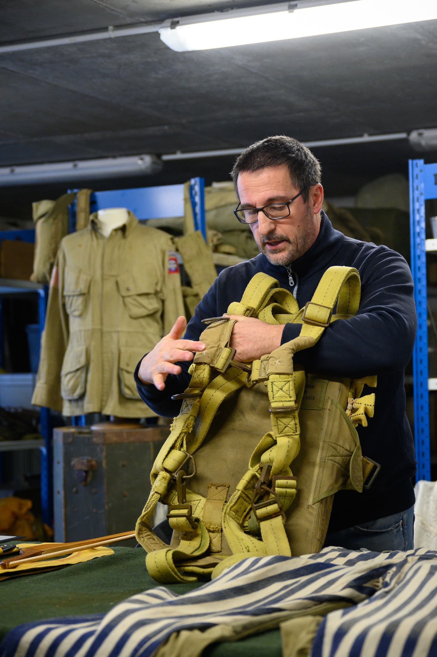 Conservator inspecting WWII parachute harness in museum storage