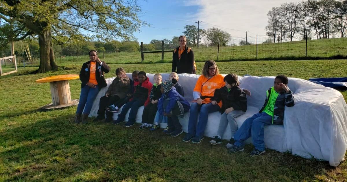 Group sitting on hay bale seating at rural pumpkin patch
