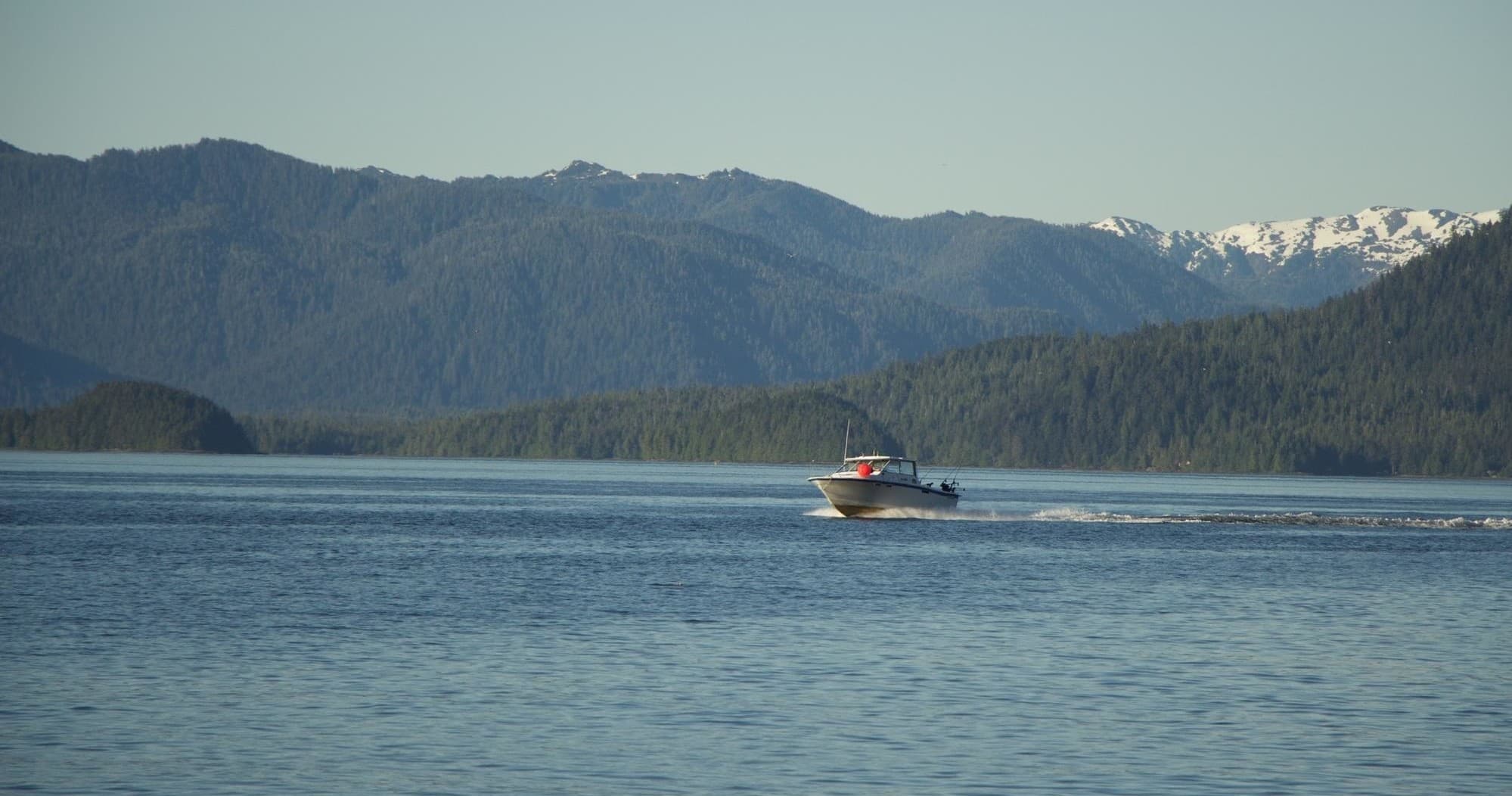 Scenic boat cruising calm Alaskan waters with mountain backdrop