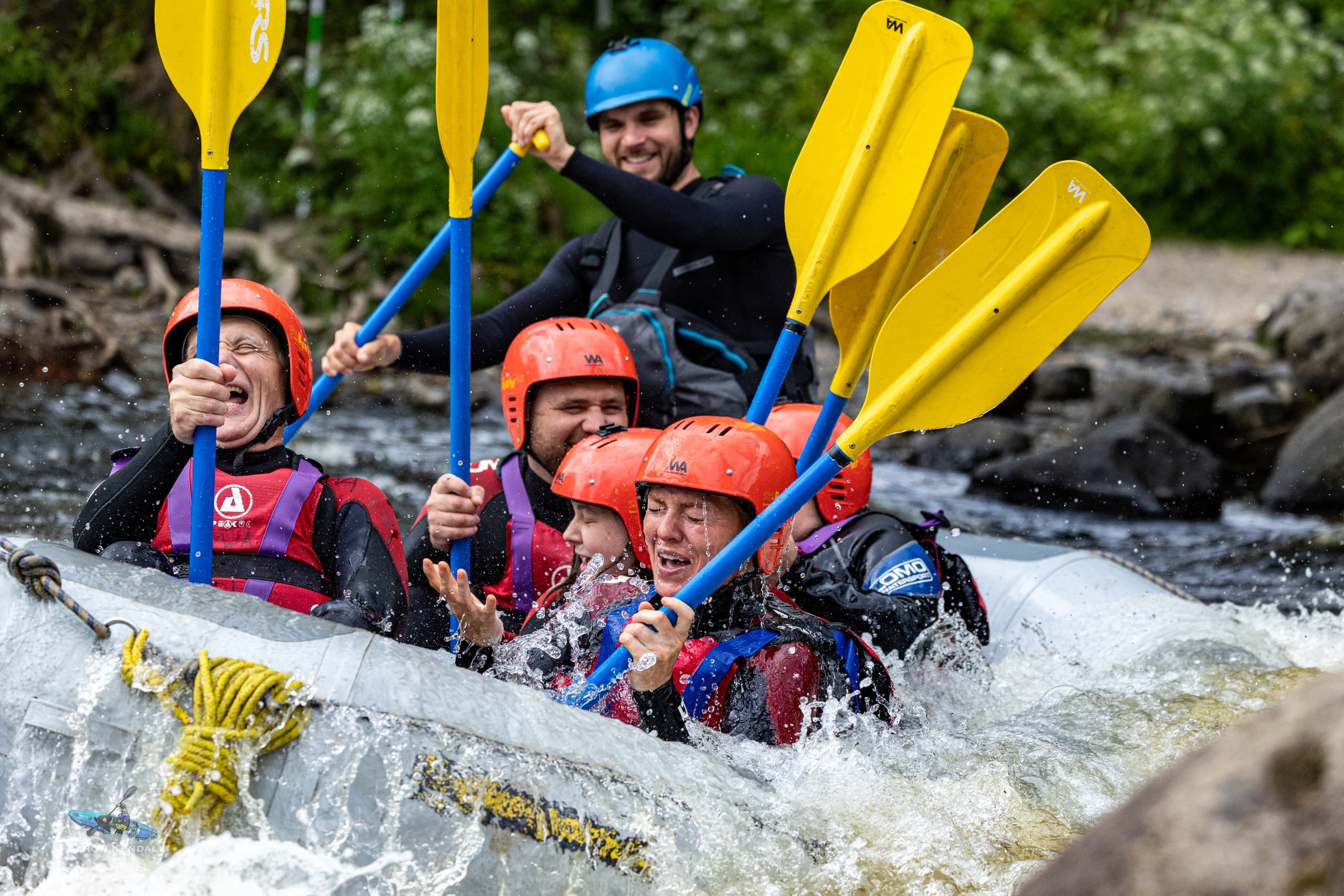 Paddlers raising yellow paddles in whitewater run