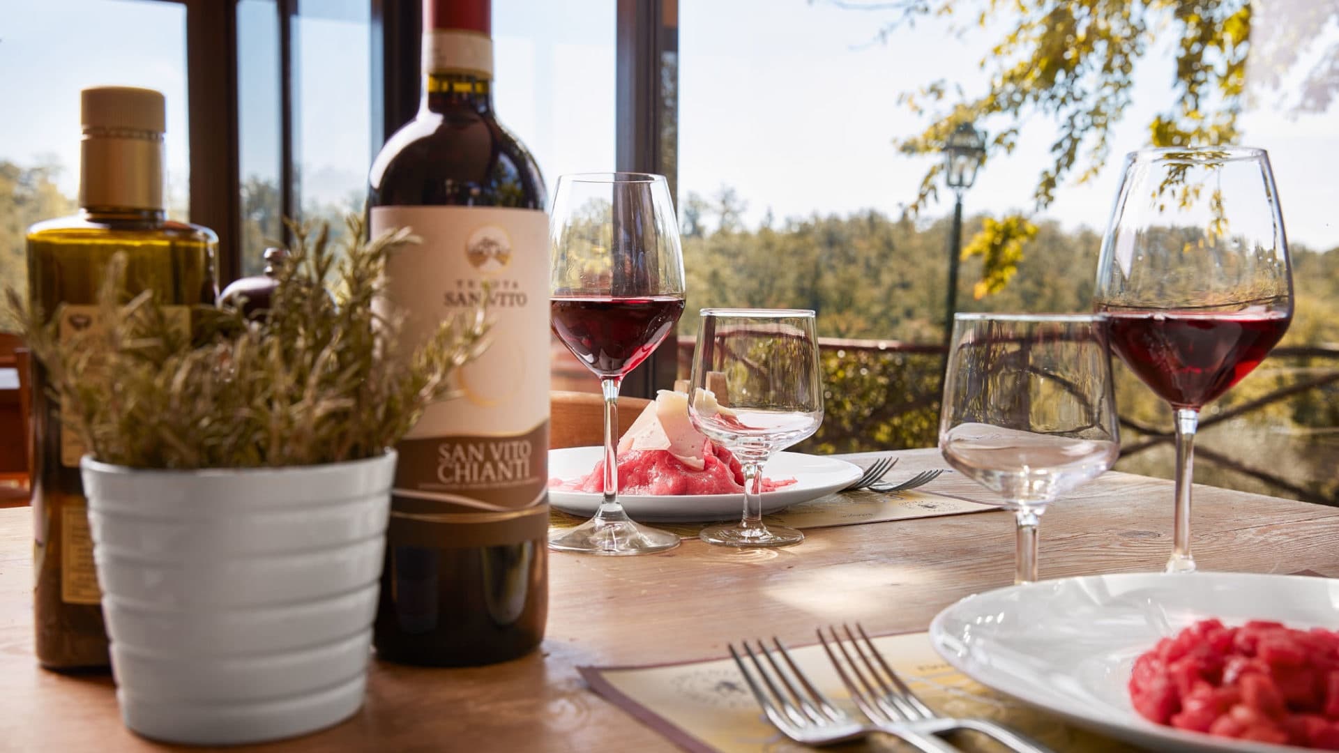 Wine glasses and bottle on outdoor terrace overlooking vineyard