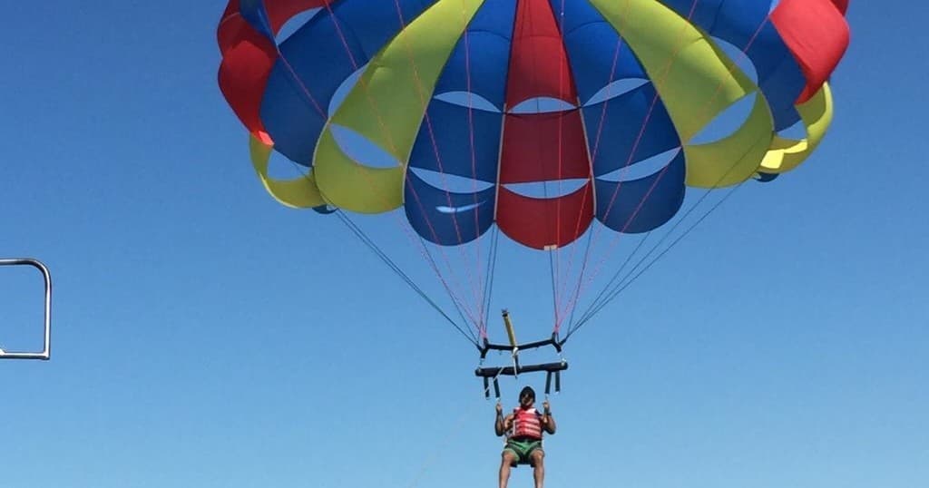 Close-up of colorful parasail canopy with rider against sky