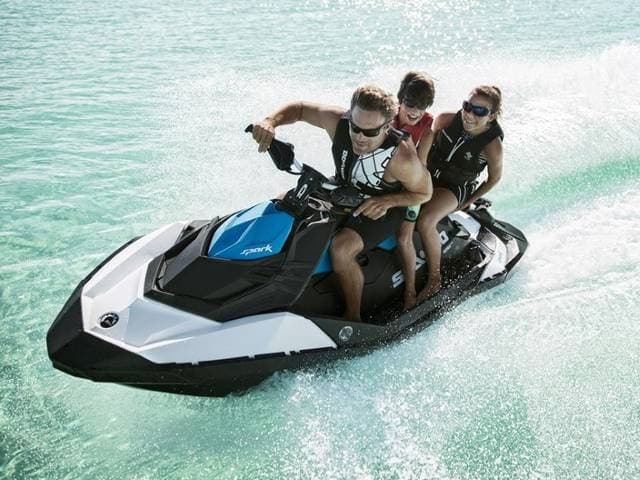 Two riders on jet ski speeding over turquoise ocean water