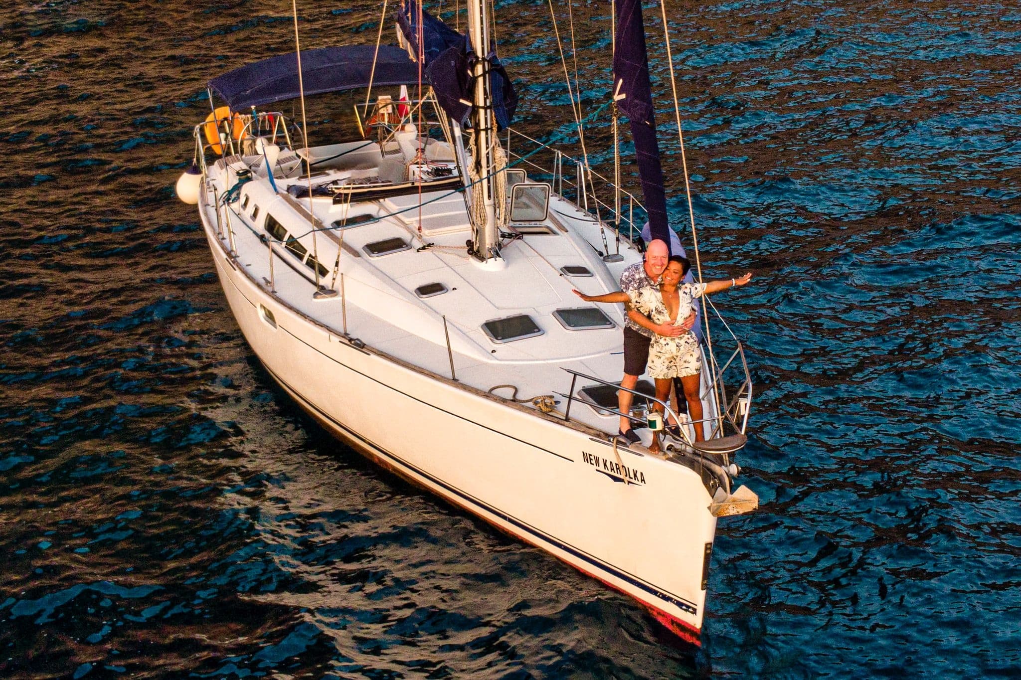 Sailboat bow slicing blue ocean waves with crew enjoying voyage