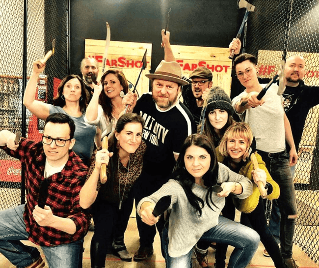 Large mixed group posing after indoor axe throwing party event