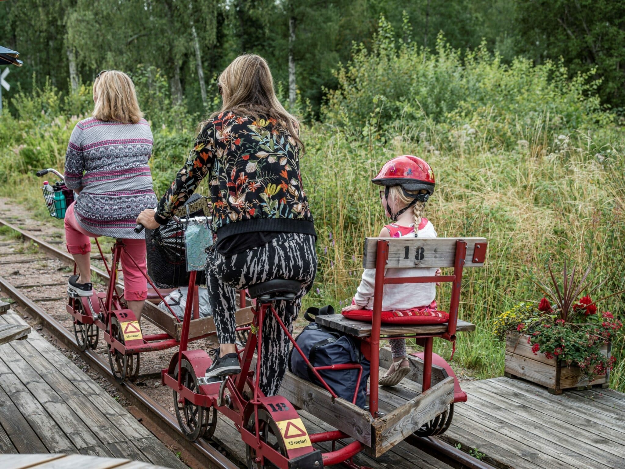 Three railbike riders cycling on wooden rail through green forest
