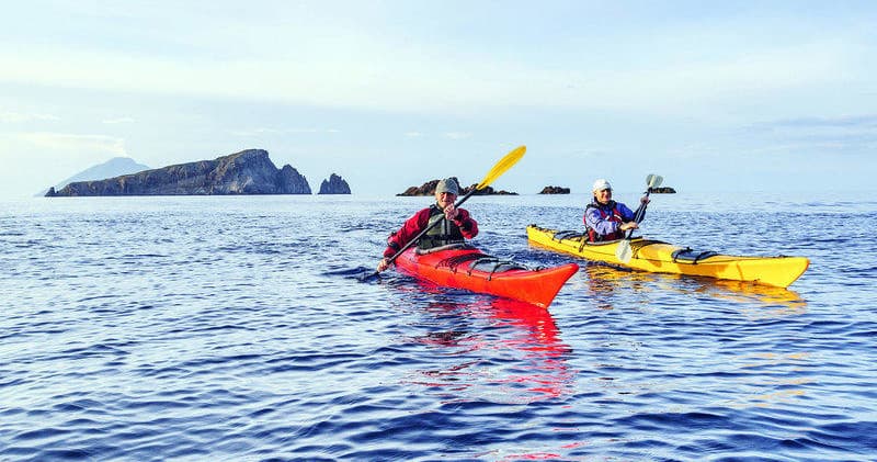 Sea kayakers paddling near coastal islands on open ocean