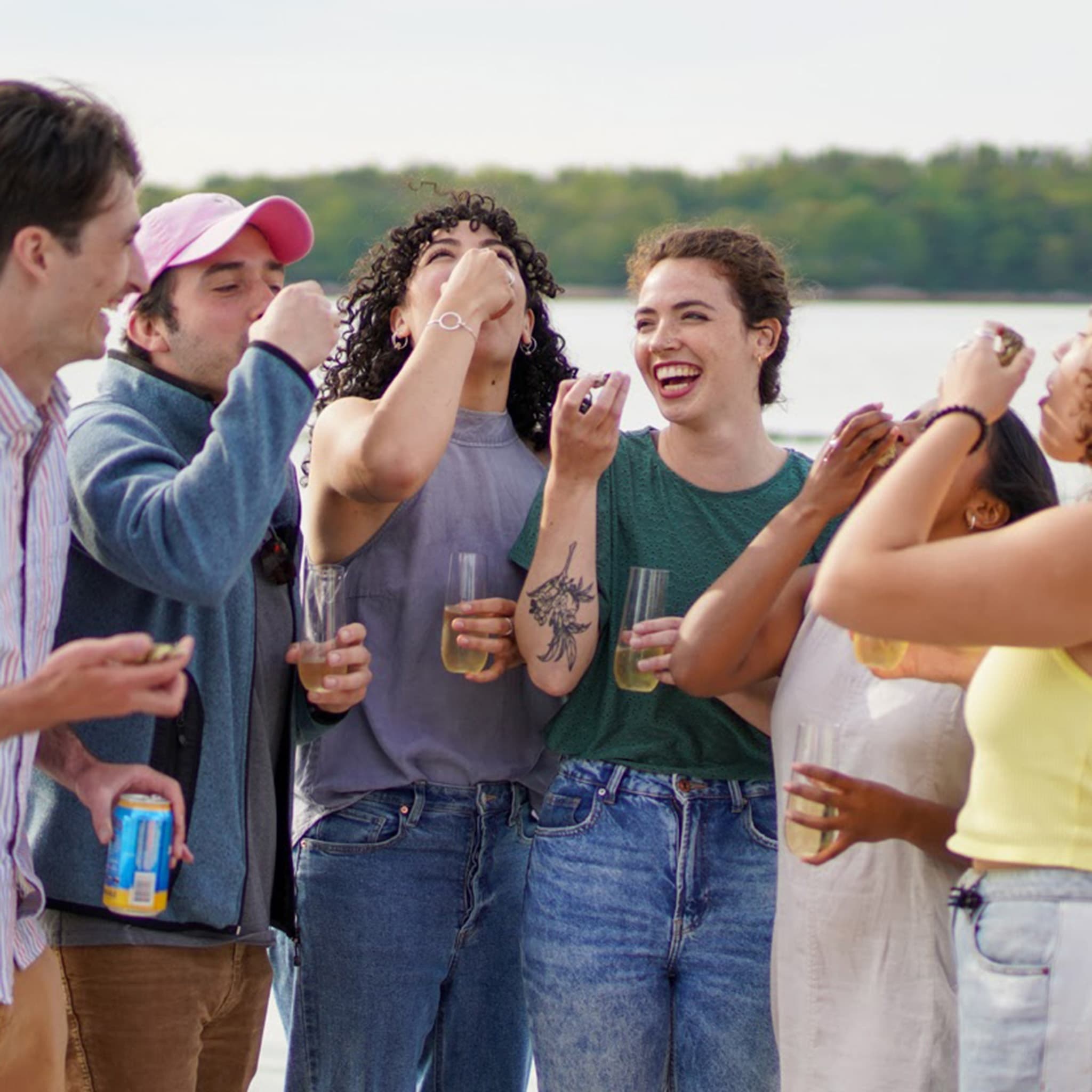 Group of friends taking shots at outdoor waterfront gathering