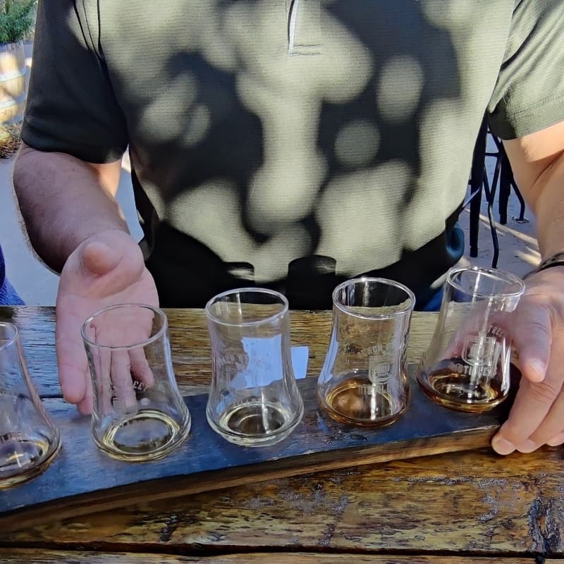 Outdoor wine tasting flight on wooden paddle at patio table
