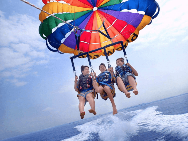 Three parasailers gliding over turquoise Caribbean ocean horizon