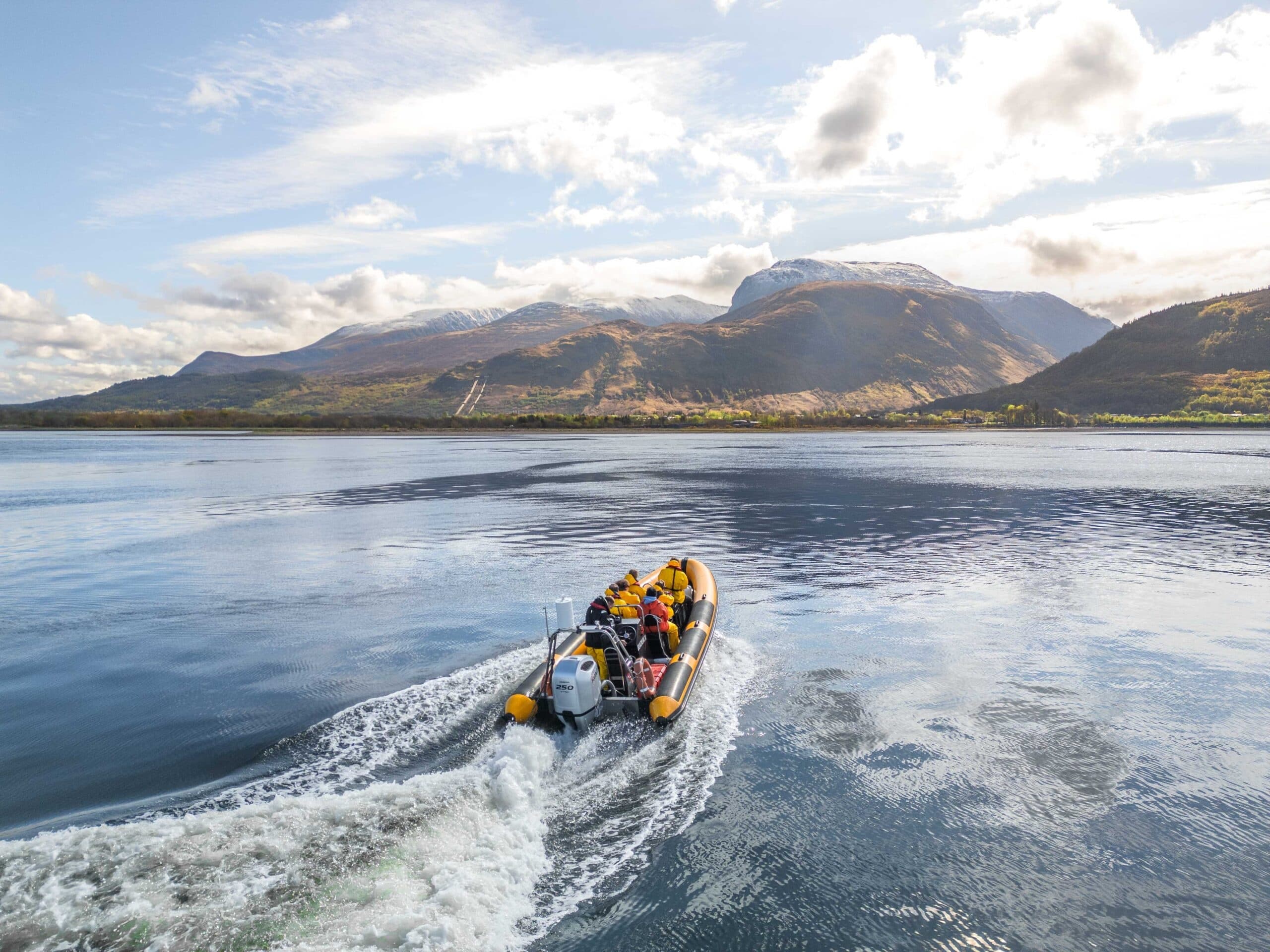 RIB speedboat cruising on alpine loch with mountain scenery