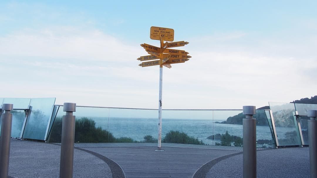 Wooden signpost at coastal viewpoint with ocean horizon