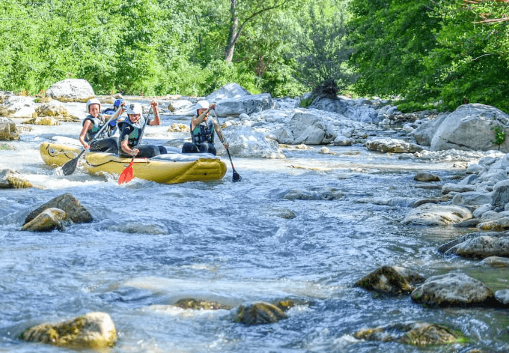 Whitewater rafters paddling down rocky river in forest
