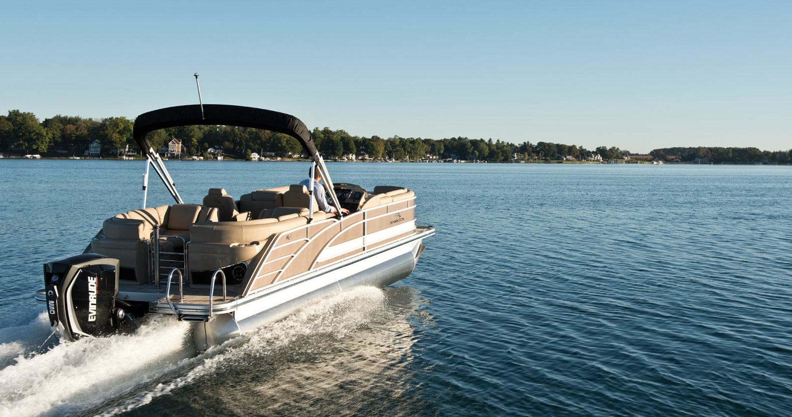 Pontoon boat cruising on a calm lake shoreline, scenic rental experience