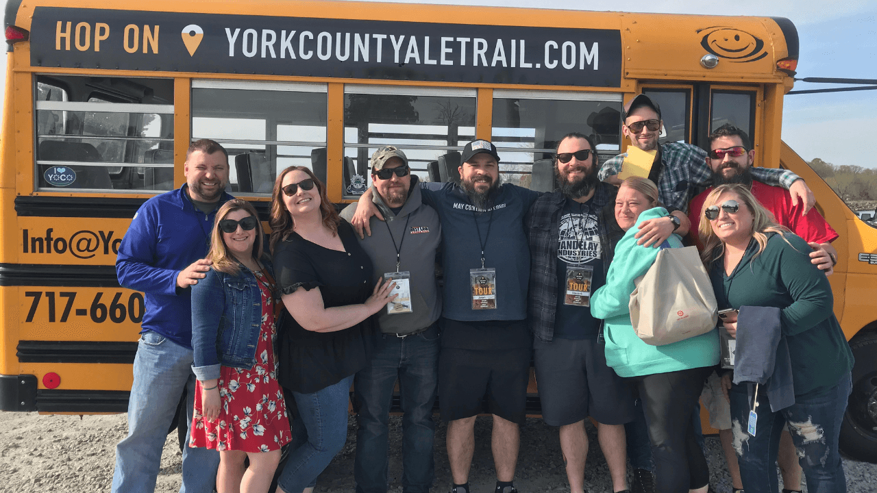Group posing by York County Ale Trail bus on brewery tour