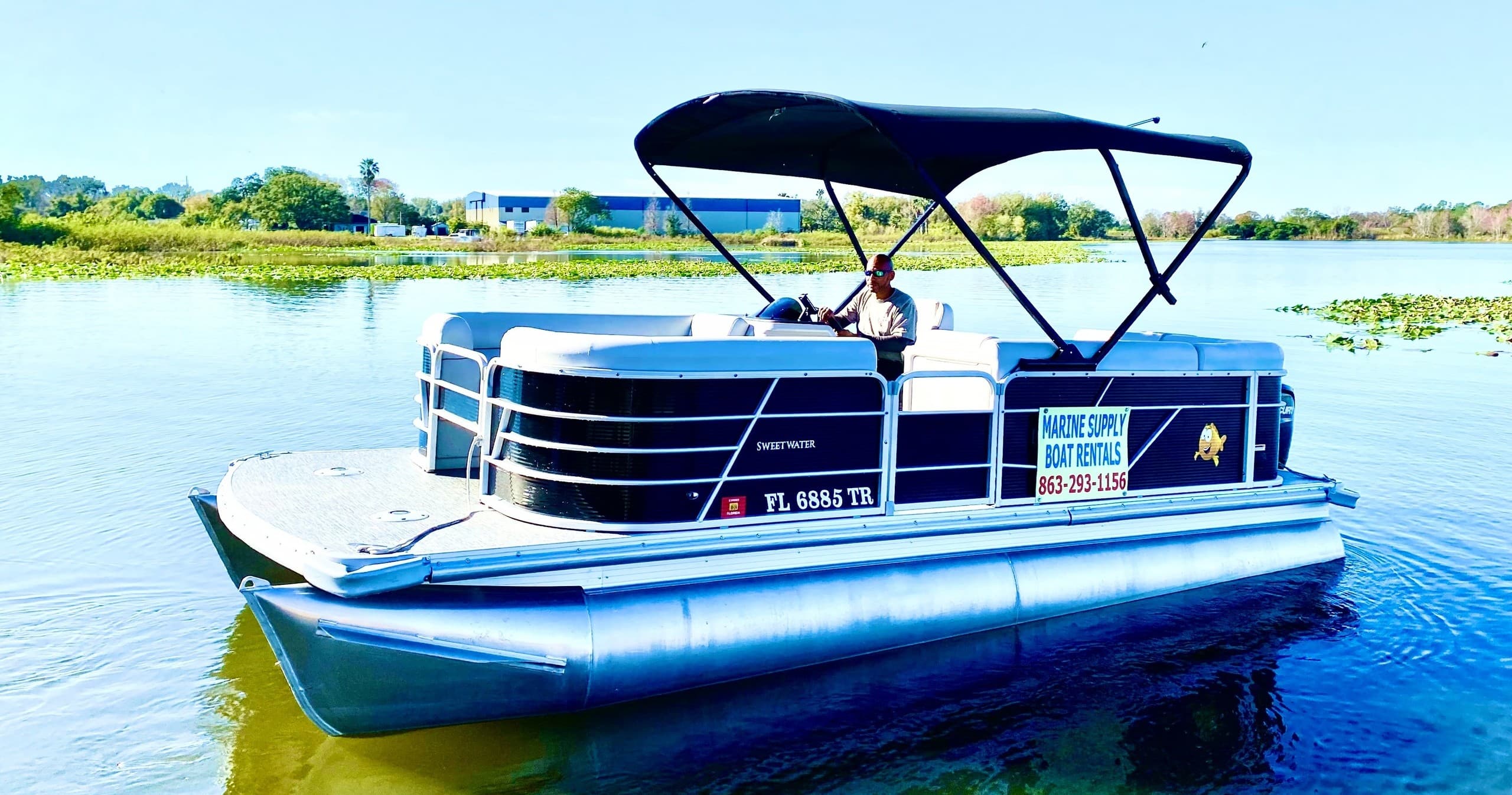 Blue pontoon boat on lake with canopy, bright sunlight