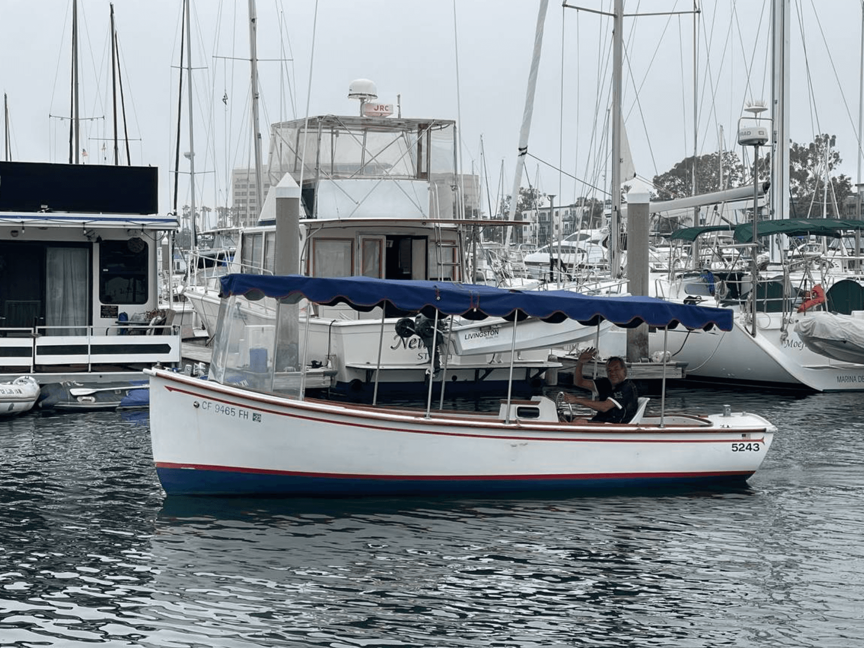 Small harbor launch moored in marina with sailboats behind