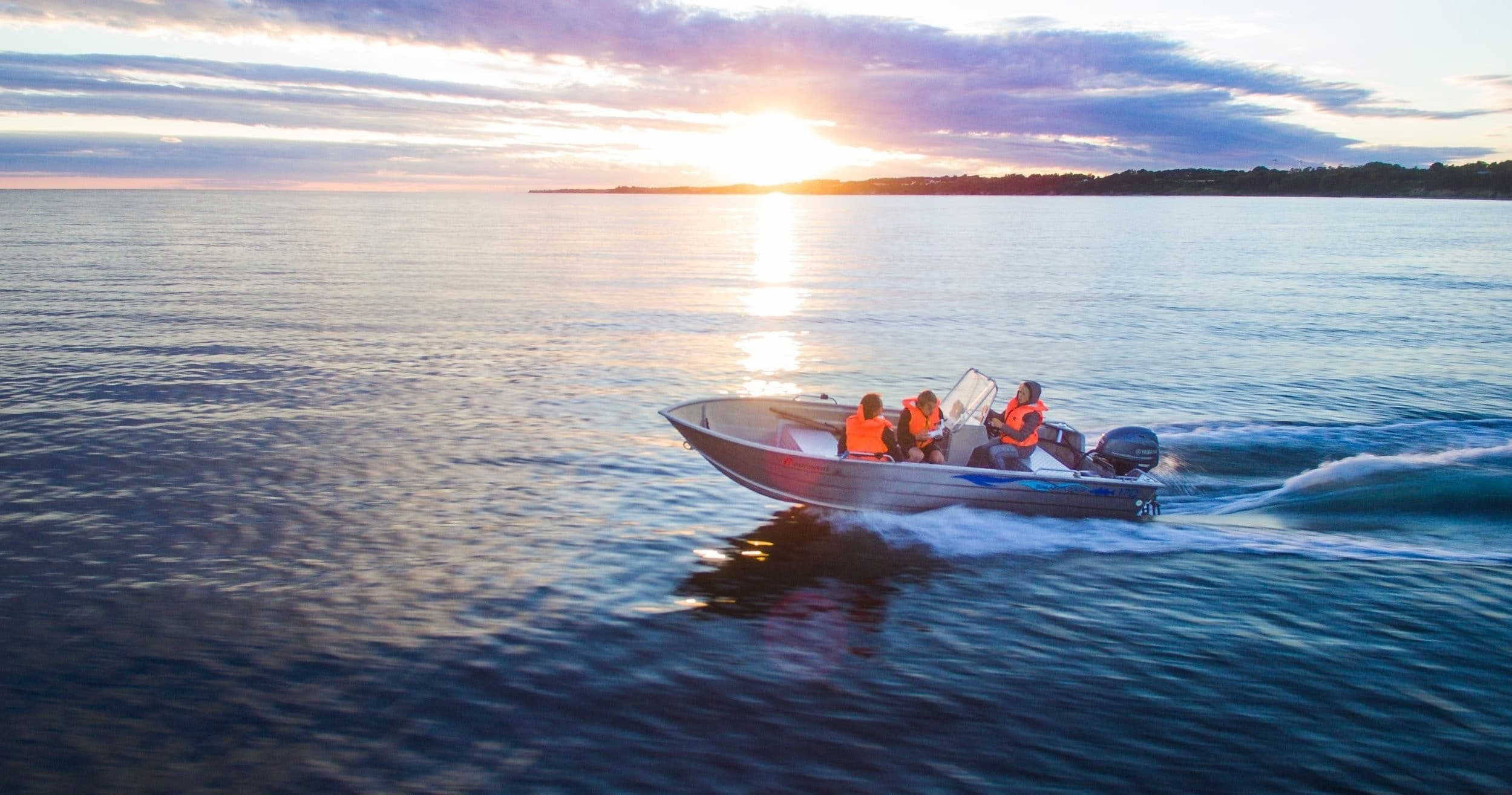 Small motorboat cruising at sunset on calm coastal waters