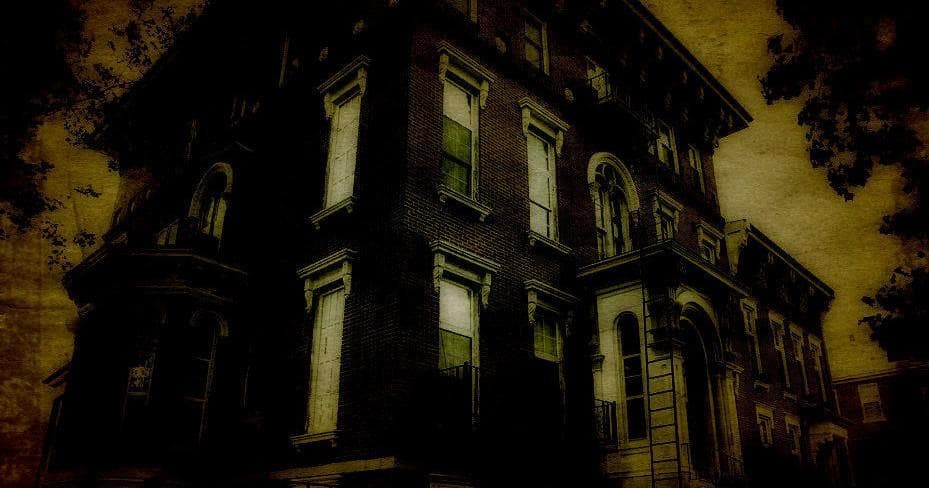 Dark Victorian corner house exterior lit by eerie streetlights