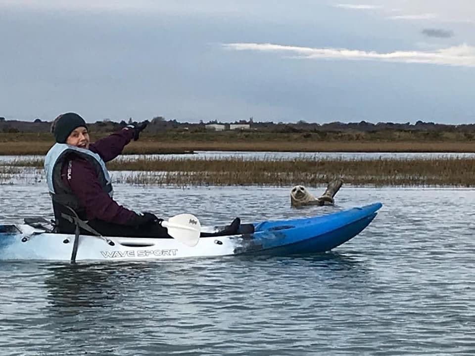 Kayaker paddling through calm estuary marsh waters