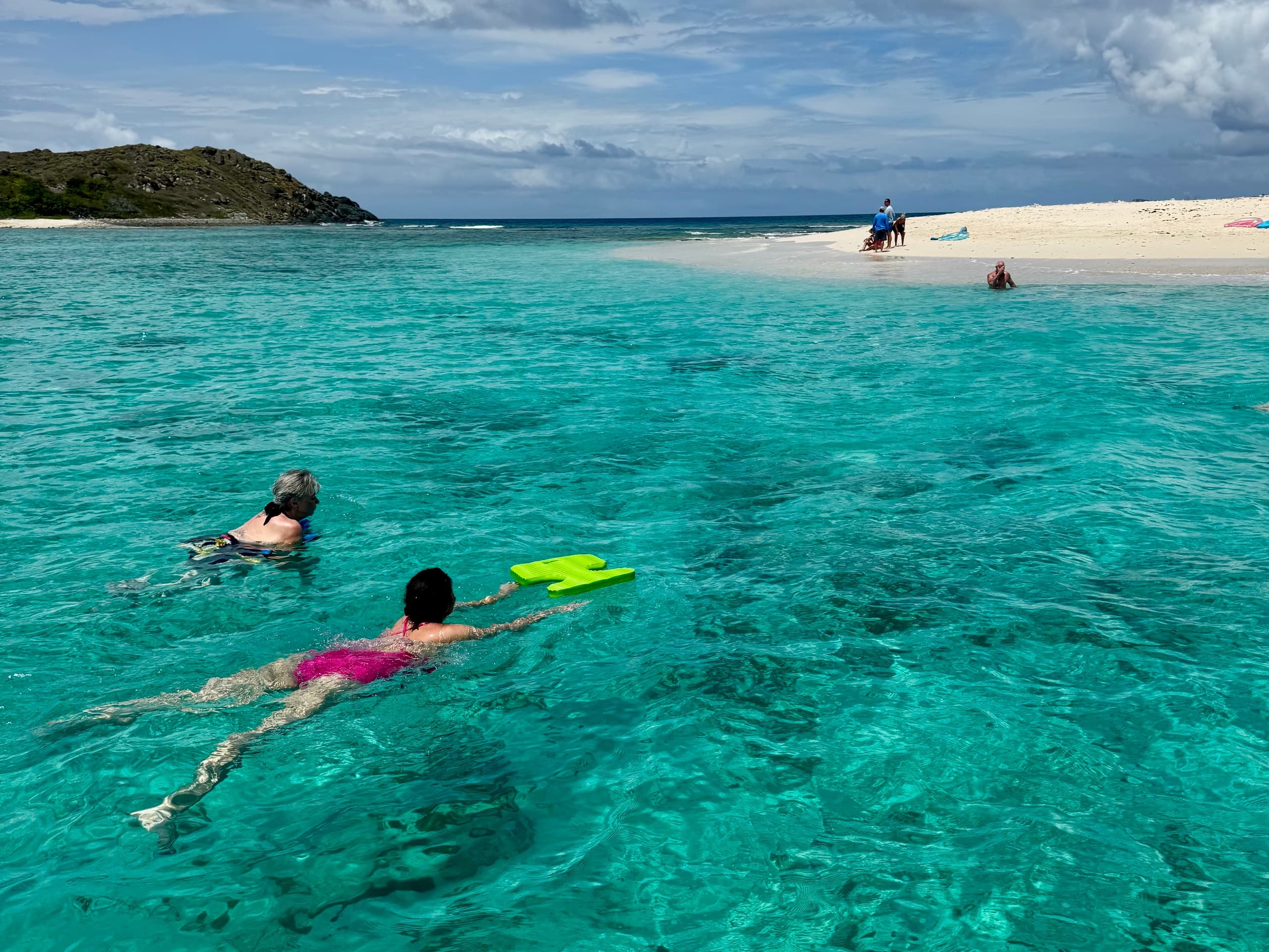 Snorkelers exploring crystal turquoise waters by sandy cay