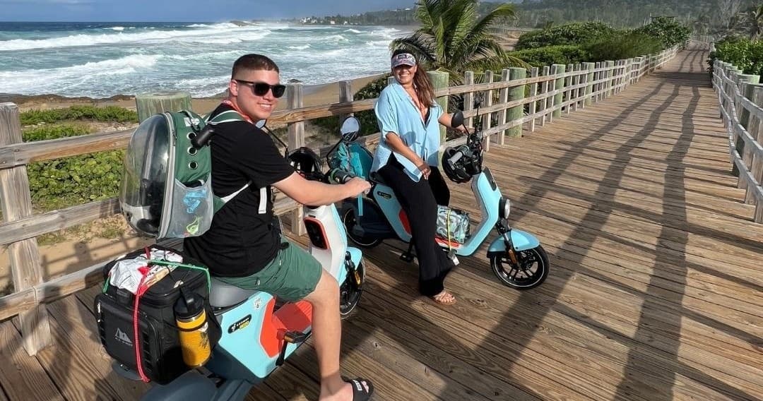 Riders on electric scooters cruising an oceanfront wooden boardwalk
