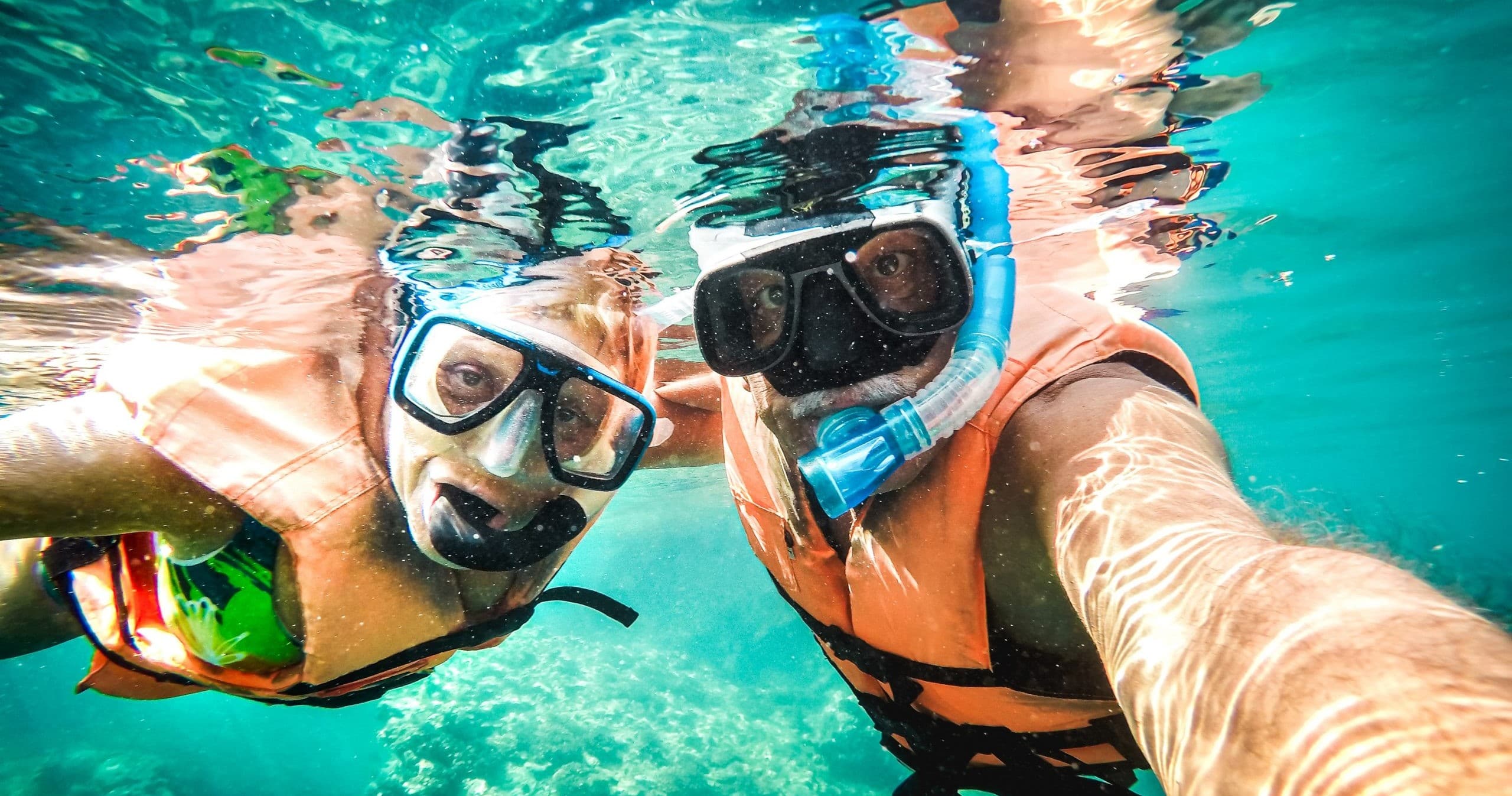 Two snorkelers taking underwater selfie in clear tropical reef waters