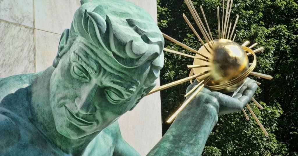 Close-up of Detroit statue holding golden orb at outdoor plaza