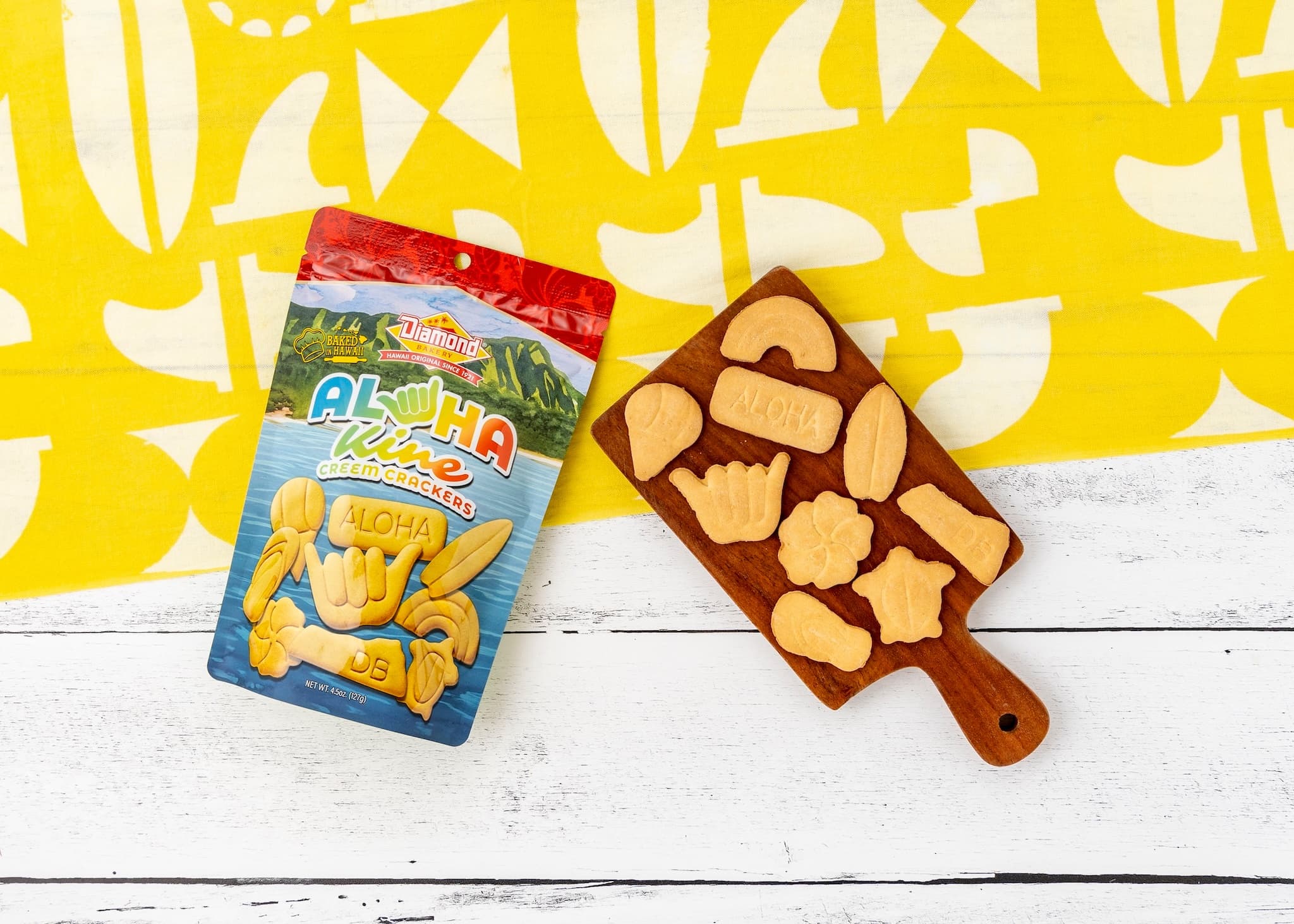 Packaged aloha-shaped cookies on wooden board, bright bakery tabletop display