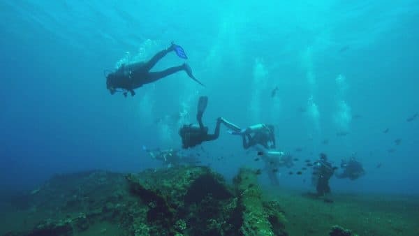 Group of divers exploring colorful coral reef underwater