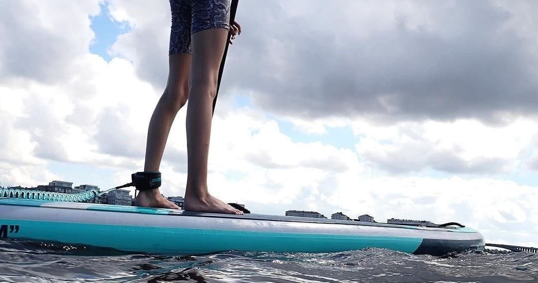 Close-up of feet on SUP with open water and sky backdrop