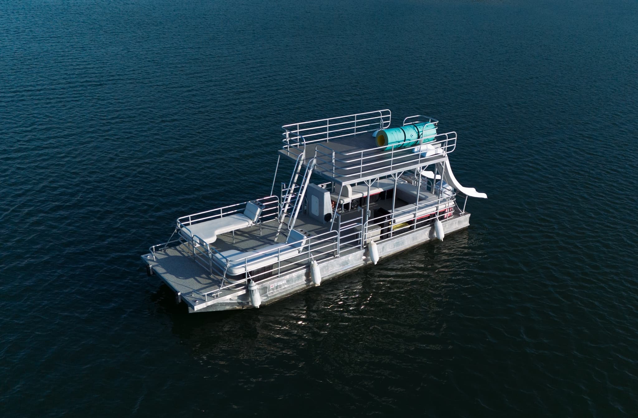 Large party pontoon cruising open water with slide and deck
