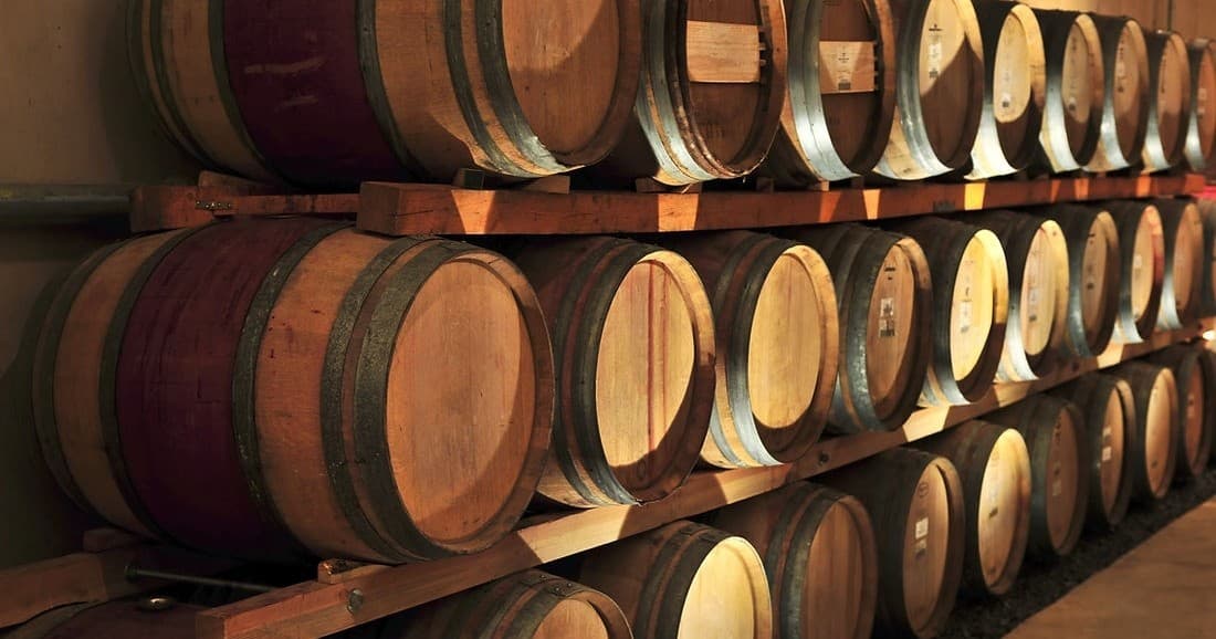 Wine barrels aging in rustic winery cellar during tasting tour