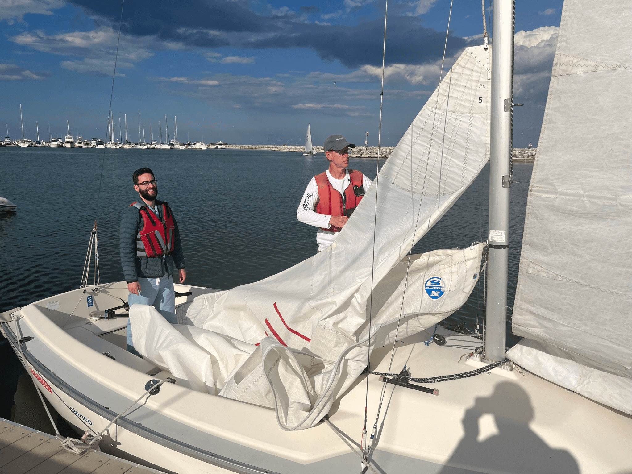 Crew preparing sails on docked sailboat at marina, hands-on