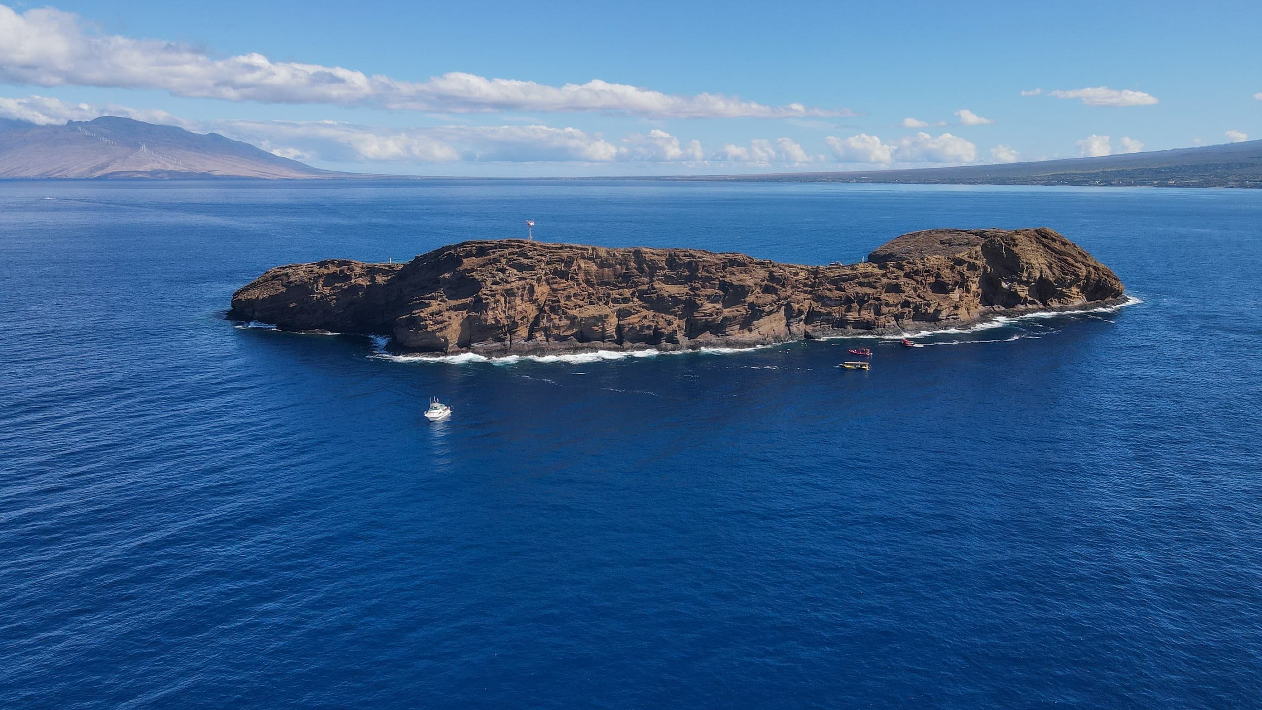 Aerial view of small volcanic island surrounded by blue ocean