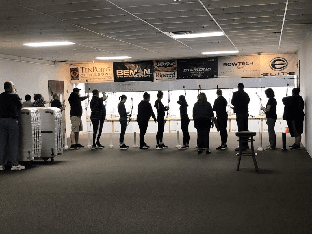 Group of archers practicing on indoor shooting line at range