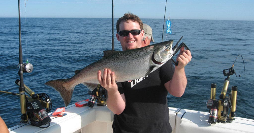 Smiling angler showing salmon catch on open ocean fishing trip