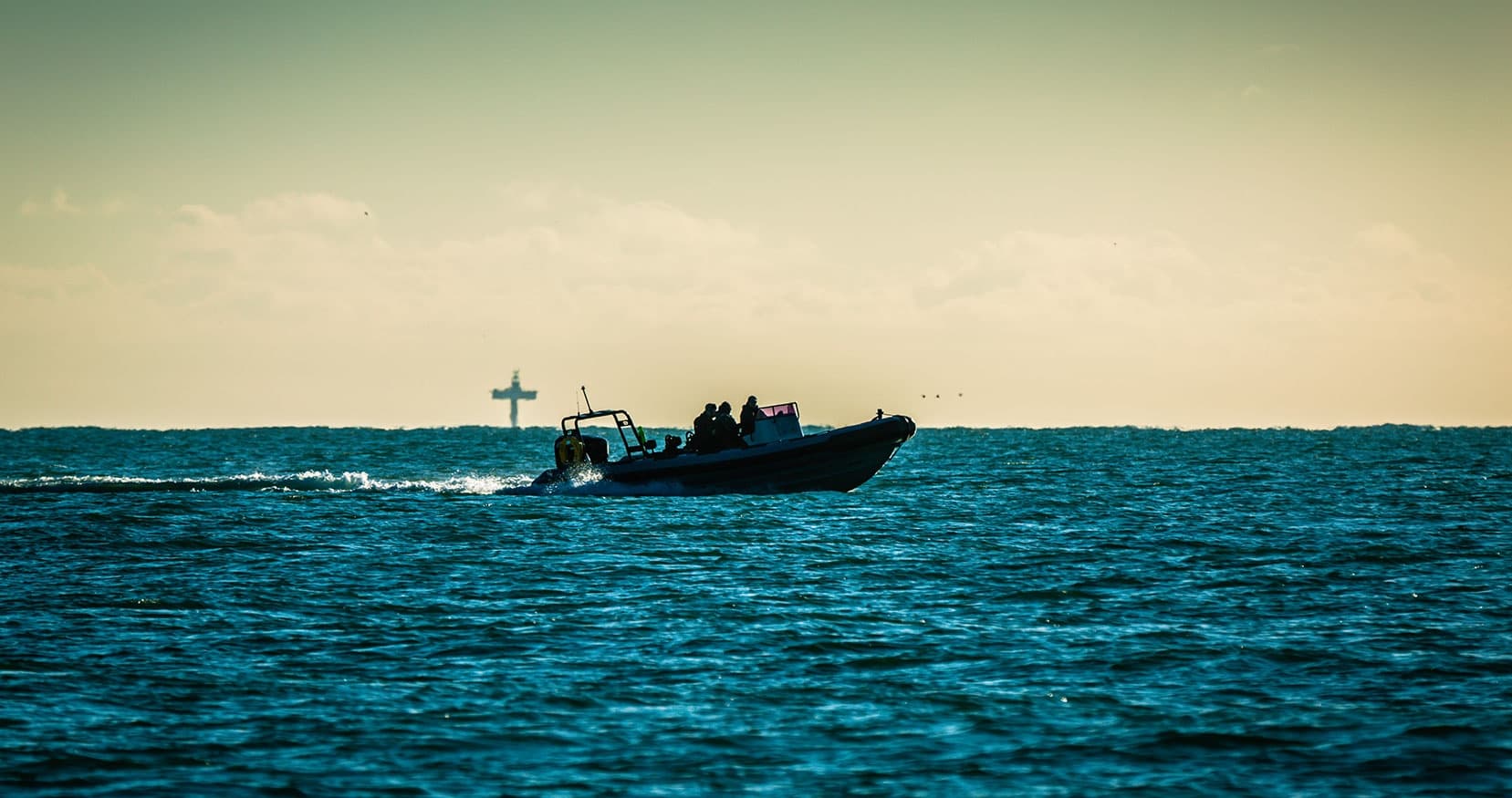 Rigid inflatable boat cruising near buoys on choppy sea
