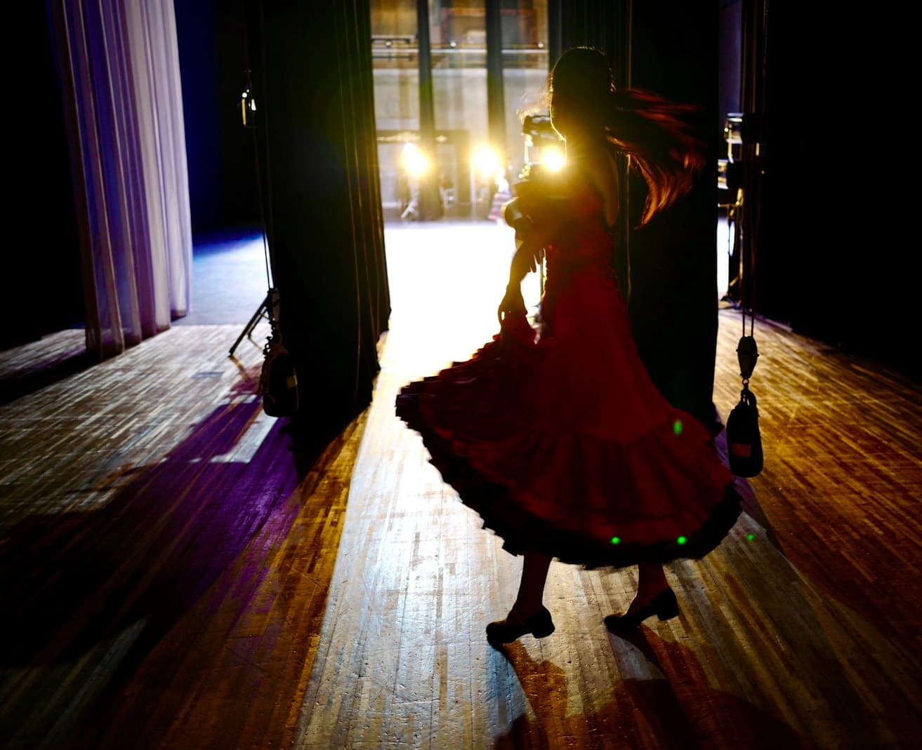 Flamenco dancer twirling on dimly lit theater stage with spotlight
