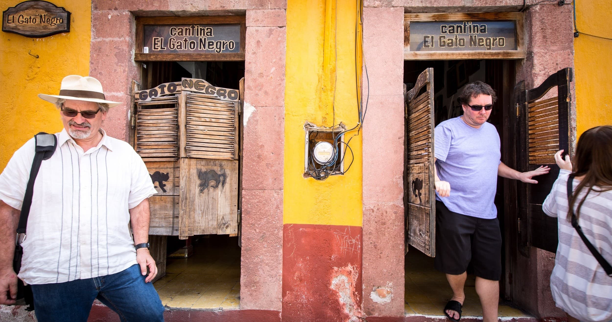 Visitors exploring colorful colonial doorways on San Miguel street