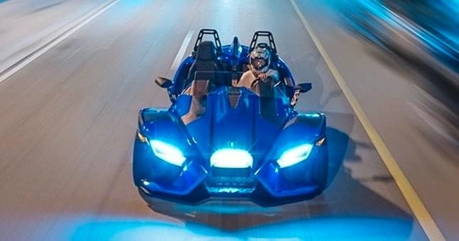 Slingshot roadster speeding at night on open road, action ride