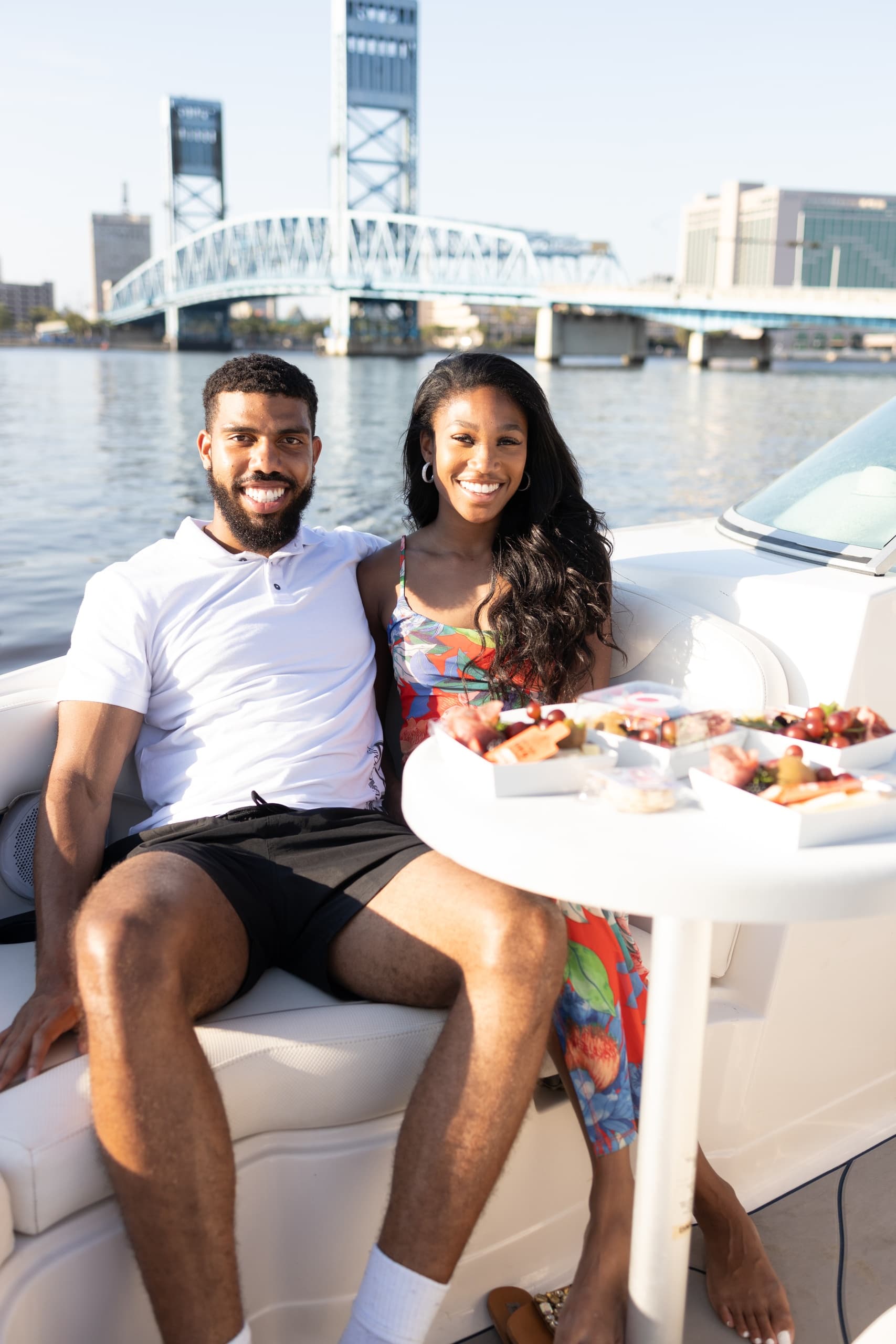 Couple enjoying boat picnic with city bridge and river
