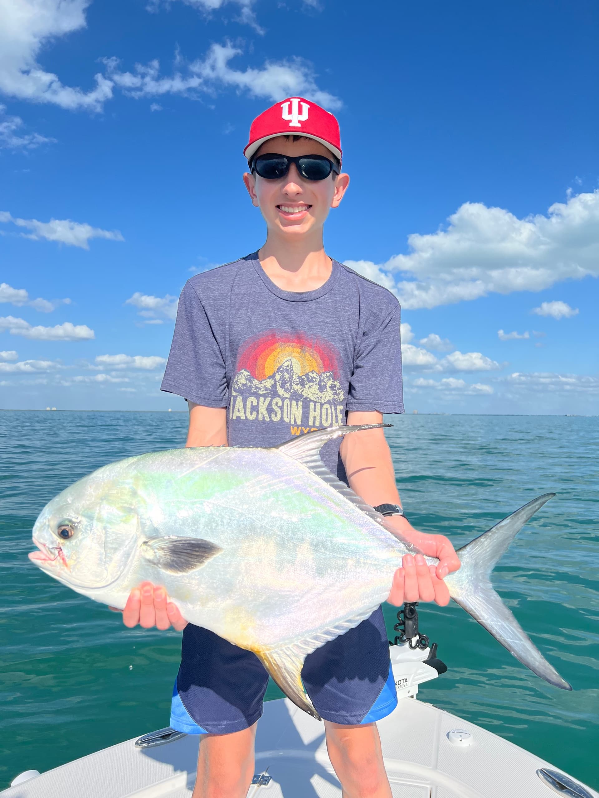 Young angler proudly holding a large saltwater fish on a charter boat