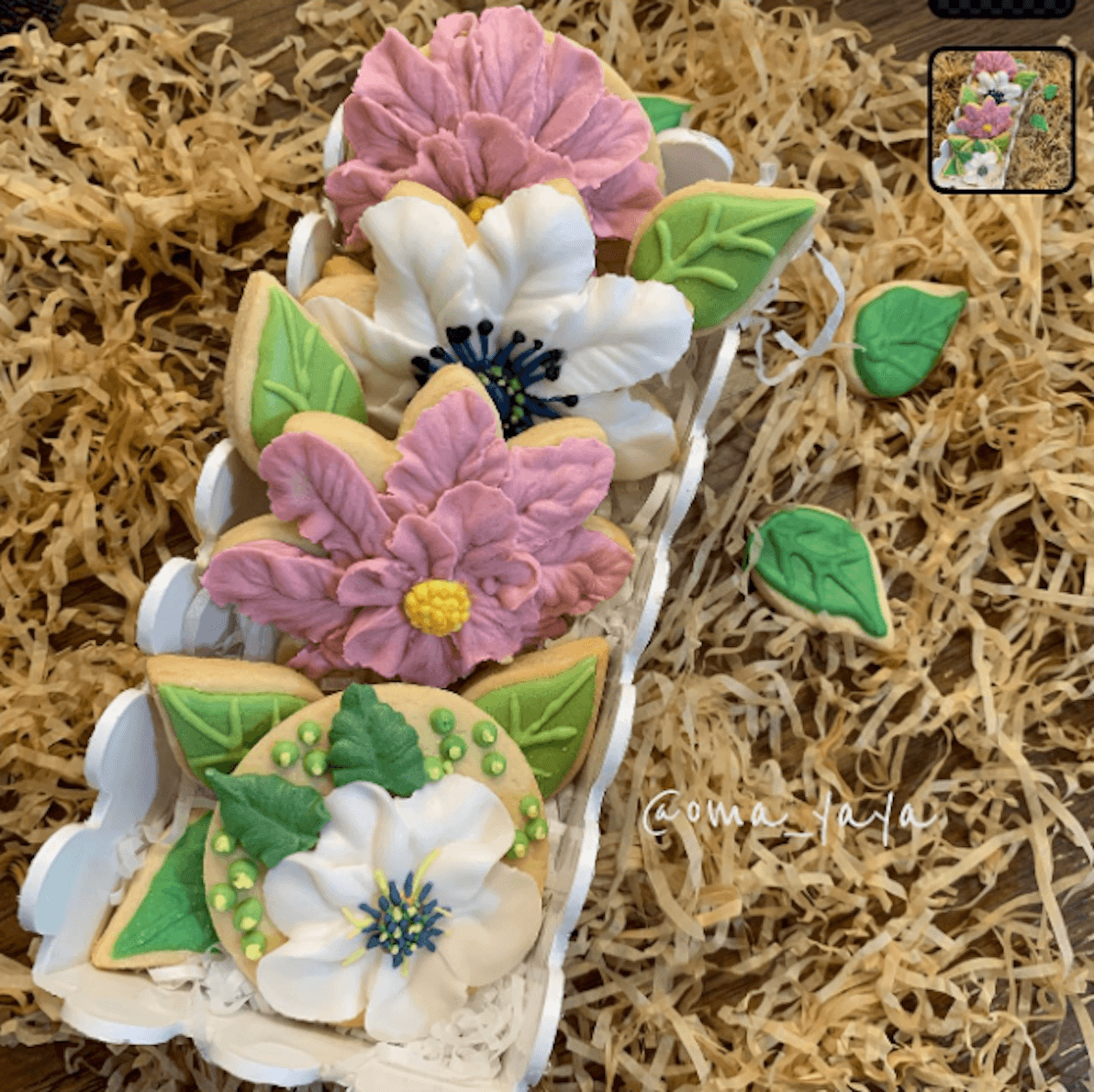 Floral decorated sugar cookies on straw bed for gift display