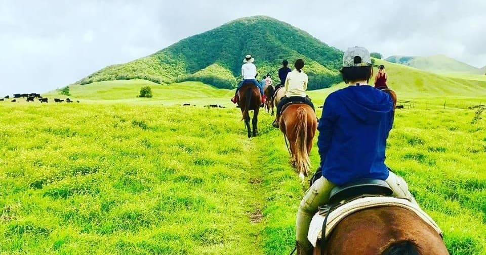 Horseback riders traversing lush green volcanic hills in Hawaii